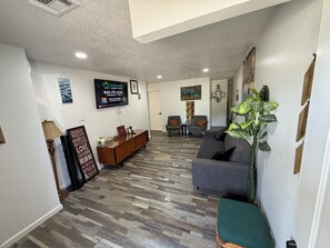 A spacious living area with a grey sofa, a wooden coffee table, and a television mounted on the wall.
