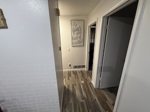 A hallway with a wooden floor, a white wall, and a motivational quote sign.