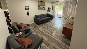 Una sala de estar moderna con un sofá gris, una mesita y suelo de madera.