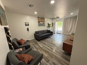 A modern living room with a grey sofa, a small table, and a wooden floor.