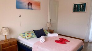 Une chambre à coucher bien rangée, avec un lit, des oreillers, une table de chevet avec une lampe et un tableau accroché au mur.