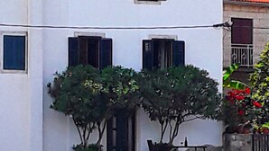 Un edificio blanco con techo de tejas rojas, plantas en macetas y un banco junto al agua.