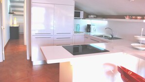 A modern kitchen with white cabinets, a microwave, a coffee maker, and a sink.