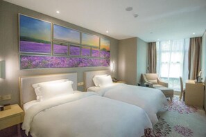 Ein Hotelzimmer mit zwei Betten, einem großen Fenster mit Vorhängen, einem Sessel und einem Kunstwerk an der Wand.
