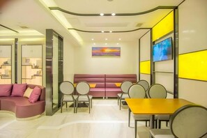 Ein modernes Interieur mit einer Couch, Sesseln und einem Tisch, inklusive eines Gemäldes und einem Fernseher an der Wand.