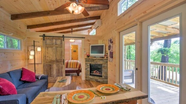 L’intérieur chaleureux d’un chalet avec un plafond en bois, une cheminée, un canapé et une table à manger.