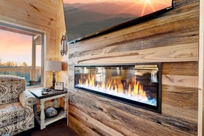 Una habitación acogedora con chimenea, un sofá y un televisor montado en la pared.