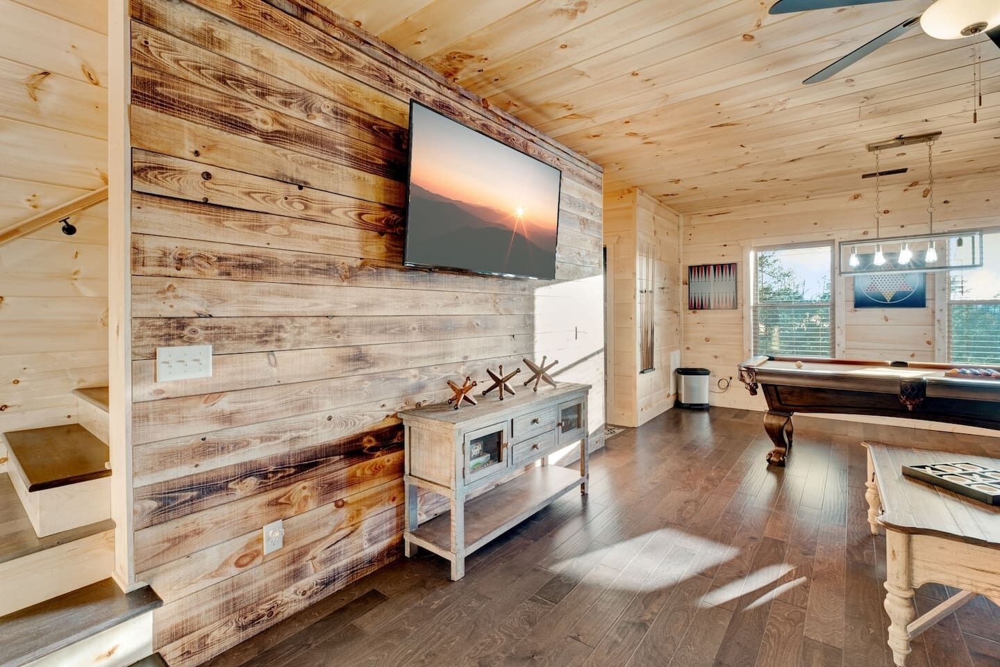 Un interior de madera con una mesa de billar, un televisor montado y un diseño de pared rústico.