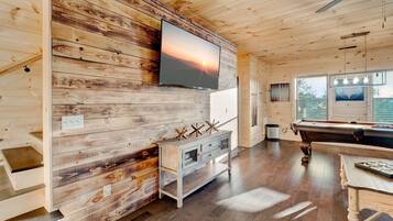 Un interior de madera con una mesa de billar, un televisor montado y un diseño de pared rústico.