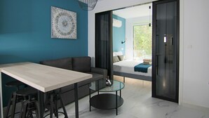 Ett modernt vardagsrum med en soffa, ett soffbord i glas, ett matbord och en skjutdörr i glas som leder ut till en balkong.
