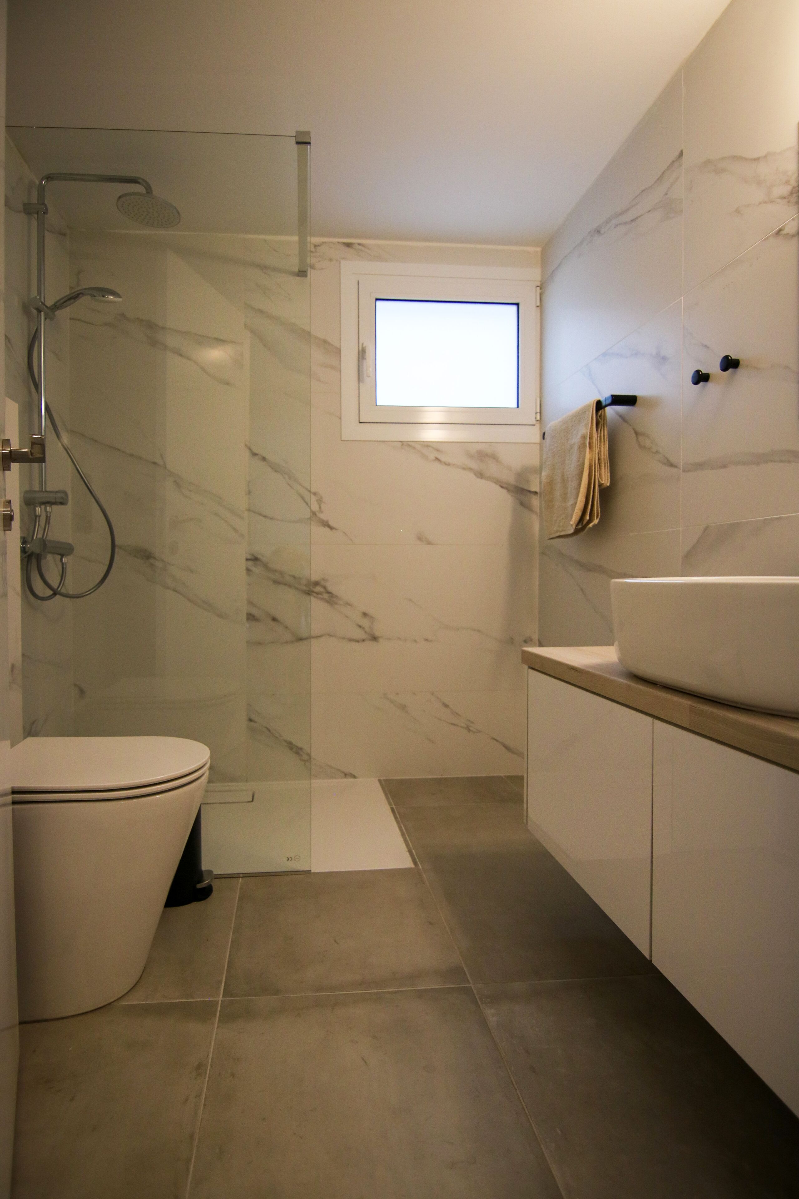 A modern bathroom with a glass-enclosed shower, a large sink, and a toilet.