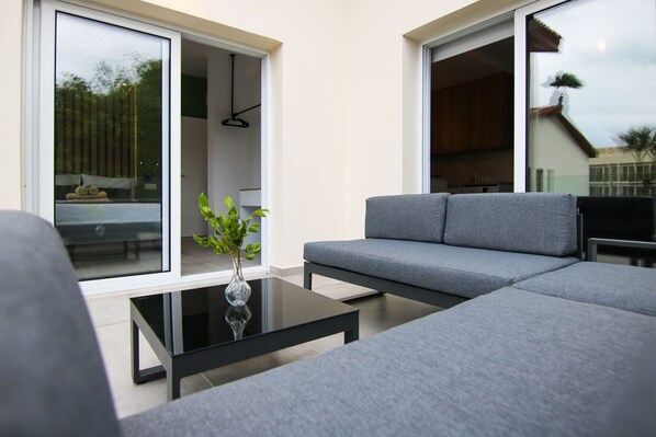 A modern living room with a grey sofa, a glass coffee table, and a vase with green plants. - Phaedrus Living: Seaside Modern Flat Limnaria 123 (Paphos)