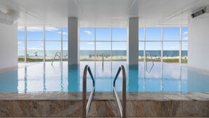 An indoor swimming pool with clear views of the beach and ocean through large windows. - Island Tower 1101 by Liquid Life (Gulf Shores)