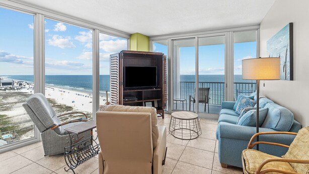 A balcony with a TV, seating, and a view of the beach. - Island Tower 1101 by Liquid Life (Gulf Shores)