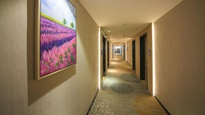 A hotel hallway with a carpeted floor, a large framed picture on the wall, and doors leading to rooms. - Lavande Hotel Guangzhou South High Speed Railway Station Huijiang Metro Station (Guangzhou)