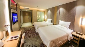 A hotel room with two beds, a TV, a desk with a chair, and a small table with a vase. - Lavande Hotel Guangzhou South High Speed Railway Station Huijiang Metro Station (Guangzhou)