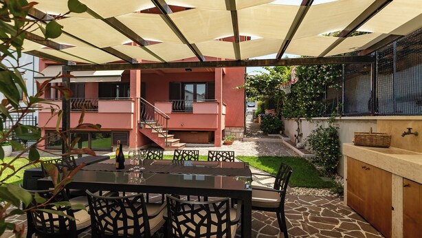 Un patio al aire libre con mesa y sillas, una parrilla y una zona de estar cubierta.