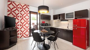 Una cocina moderna con una mesa de comedor, sillas, un televisor y un refrigerador rojo.