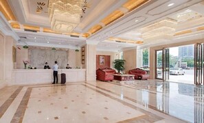 Eine Hotelhalle mit Empfangstresen, Sitzgelegenheiten und großen Fenstern.