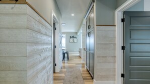 A hallway with a wooden floor, a gray door, and a wall with a 'father' sign. - Traverse City Lakemore Resort,  New Luxury Lakefront Home on Arbutus Lake (Traverse City)
