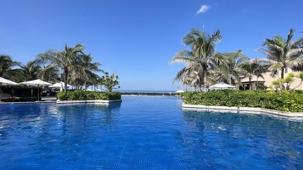 A swimming pool with palm trees and a clear sky. - Suite & Pavilion Thien Kim (Cam Lam)