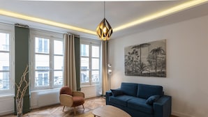 A modern living room with a blue sofa, a wooden coffee table, and a hanging light fixture. - Le Confident - Grand T2 au coeur de Lyon (Lyon)
