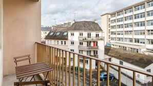 A balcony with a wooden bench, overlooking a street with buildings and parked cars. - LORGERIL - appartement 2 chambres proche du Mail (Rennes)
