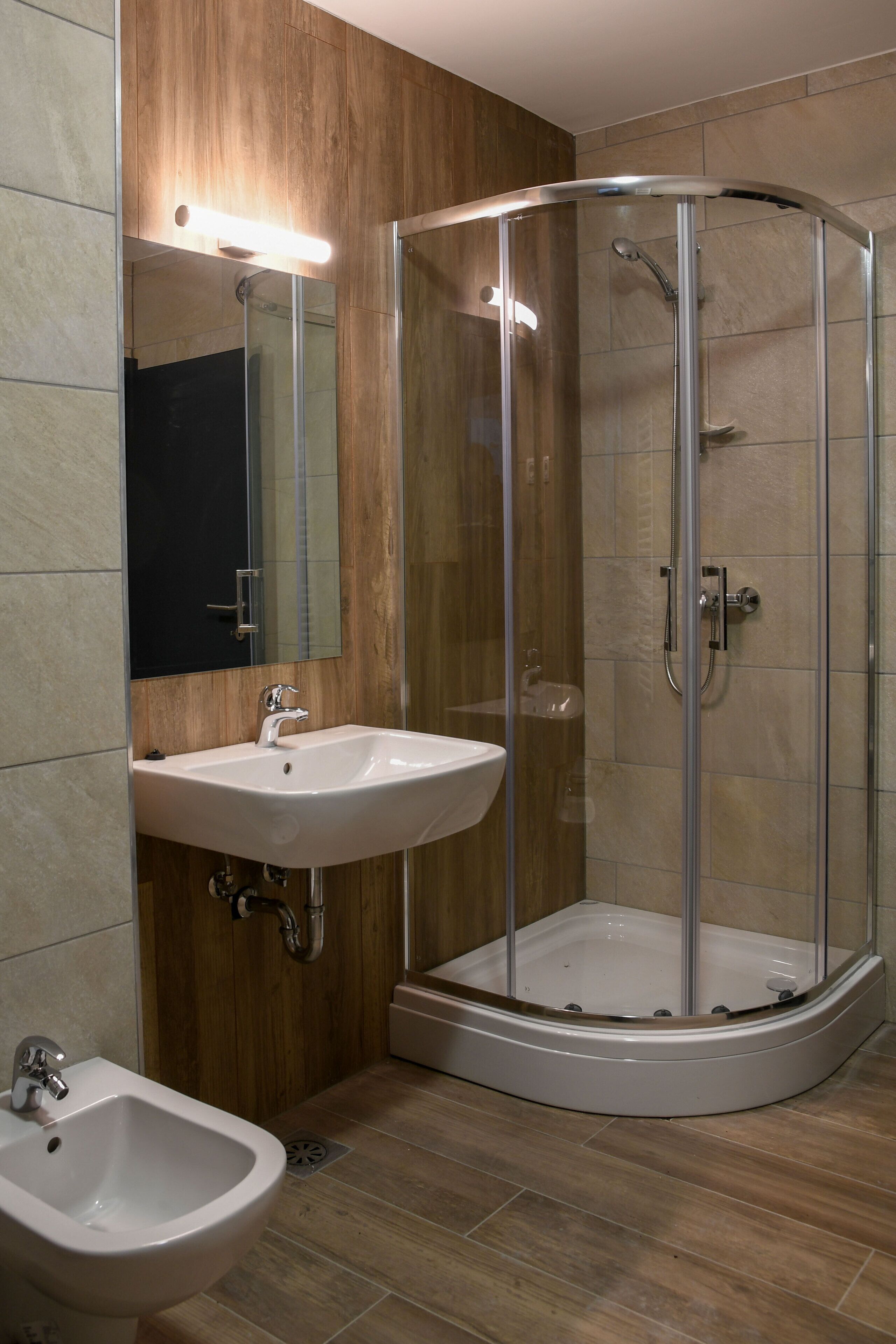 A modern bathroom with a glass-enclosed shower, a sink, and a bidet.