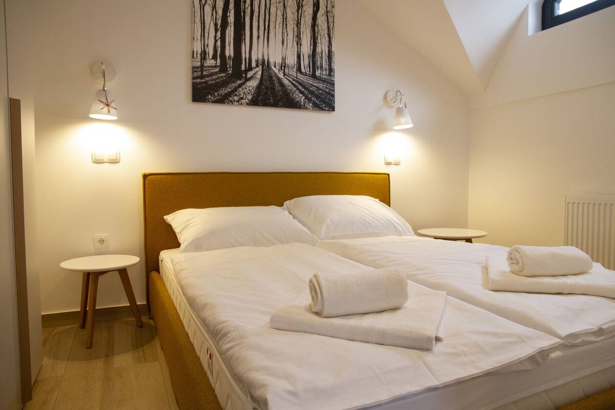 A hotel room with a large bed, two bedside tables, and a painting on the wall.