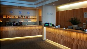 Un espace d’accueil comprenant un comptoir en bois, une horloge et un bar avec diverses bouteilles.