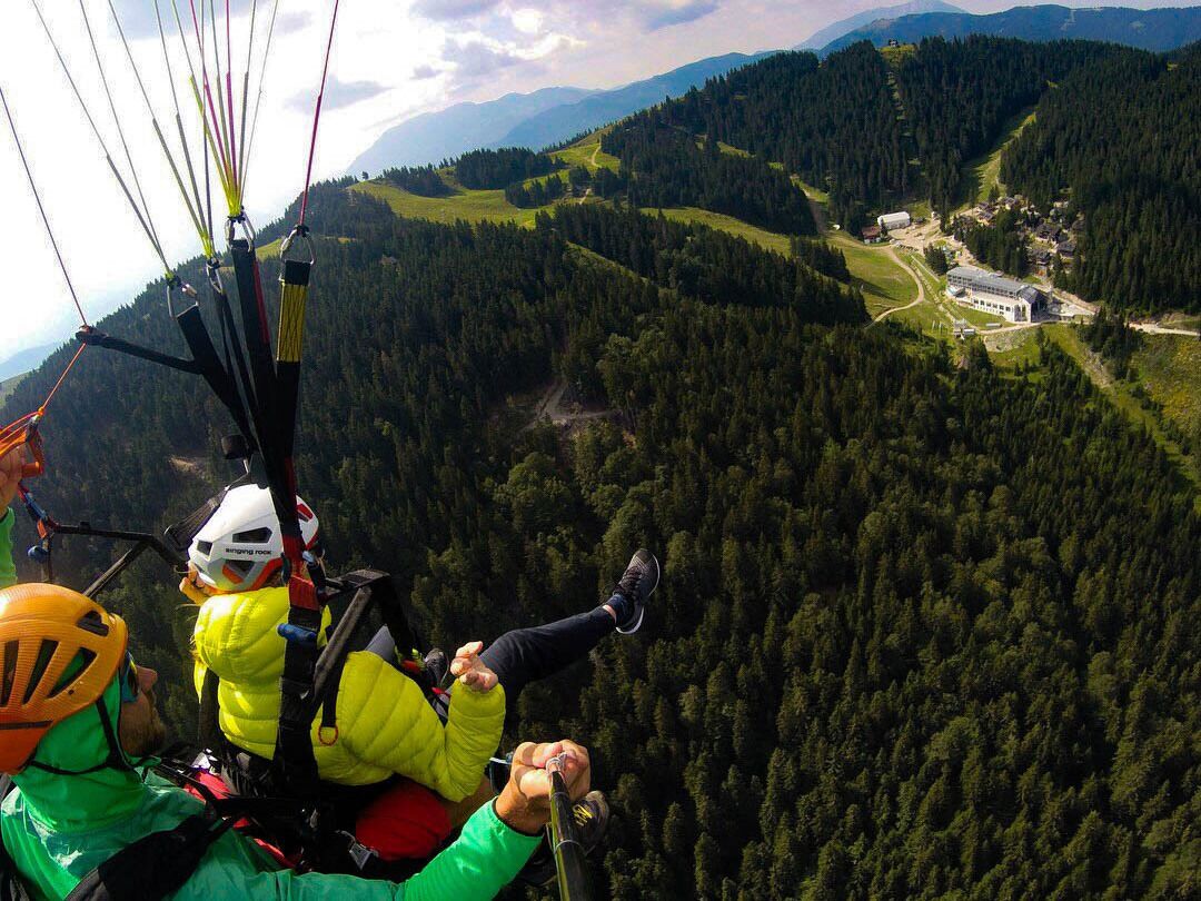 A person in a yellow jacket and helmet preparing to rappel down a mountain.