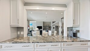 A kitchen with white cabinetry, a marble countertop, and a built-in espresso machine. - 8 Dinghy - BOOK MEMORIAL WEEKEND - 4 Night Special in an Oceanfront Home! (Hilton Head Island)