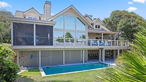A two-story house with a large balcony, a swimming pool, and a covered patio area.