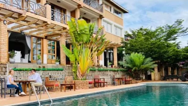 Zona de piscina con mobiliario exterior y un edificio con balcón.