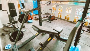 Un gimnasio con diversos equipos de ejercicio, incluyendo una prensa de banca, un rack para sentadillas y accesorios para levantamiento de pesas.
