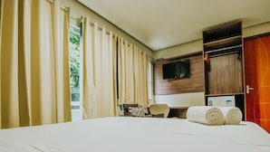 Habitación de hotel con una cama grande, un escritorio con una silla, un televisor montado en la pared y un armario.