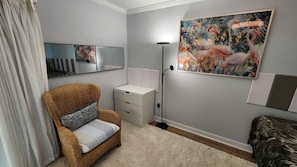 A bedroom with a bed, a chair, a bedside table, a floor lamp, a painting, and a mirror. - Great location with ocean view  . (Venice)