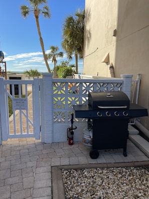 A barbecue grill with a gas tank, a white gate with a 'No Trespassing' sign, and palm trees in the background. - Great location with ocean view  . (Venice)