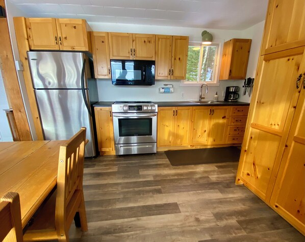 Een keuken met houten kasten, roestvrijstalen apparatuur en een raam dat natuurlijk licht binnenlaat.