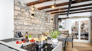 A kitchen with a stone wall, modern appliances, and a dining area with natural light. - Dal Pescatore Apartment in the Old Town (Rovinj)