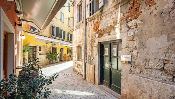 A narrow cobblestone street with a café bar named 'caffè bar KRISTAL' and a building with a stone facade and a green door. - Dal Pescatore Apartment in the Old Town (Rovinj)