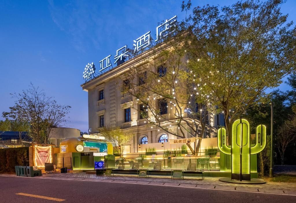 A hotel with a prominent sign, outdoor seating area, and a large illuminated cactus decoration.