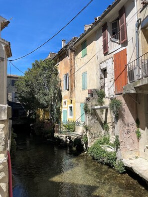A narrow waterway flanked by buildings with stone walls and wooden shutters.