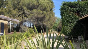 A garden with a gravel path, green plants, and a building with a tiled roof. - Villa 6km from St Rémy de Provence with swimming pool for 2 to 10 people (Eyragues)