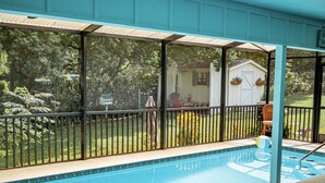 A swimming pool with a covered area, a fenced yard, and a house in the background. - Dora Splash Pad (Mount Dora)