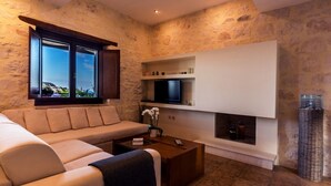 Ein modernes Wohnzimmer mit einem beigen Sofa, einem Couchtisch, einem flachbildfernseher an einer weißen Wand und einem Kamin.