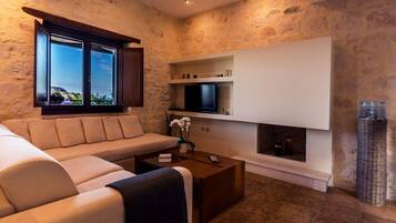 Una sala de estar moderna con un sofá beige, una mesa de centro, un televisor de pantalla plana montado en una pared blanca y una chimenea.