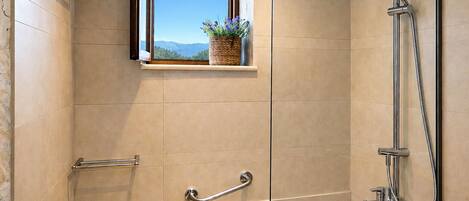 Un baño moderno con cabina de ducha de vidrio, una ventana con vistas y un inodoro.