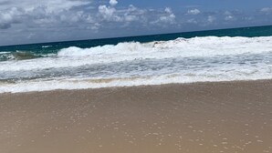 A beach with waves crashing onto the shore under a clear sky.