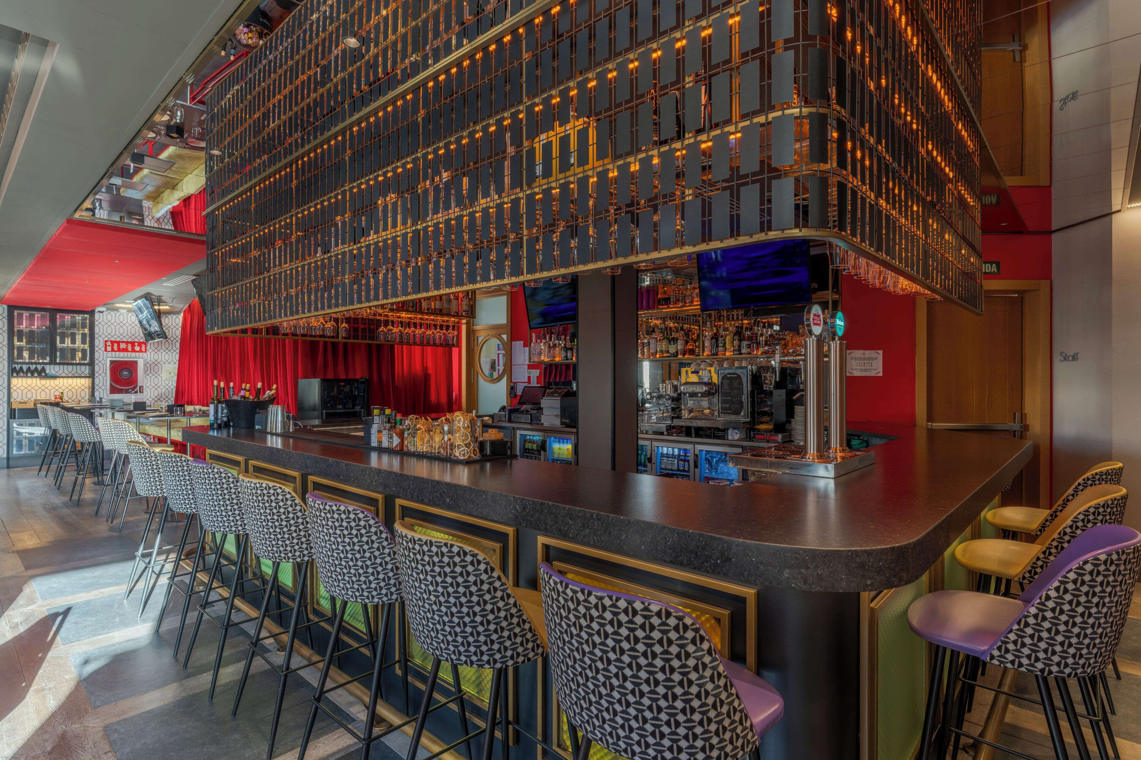 A bar area with a high ceiling, multiple levels, and a variety of seating options including bar stools and chairs.
